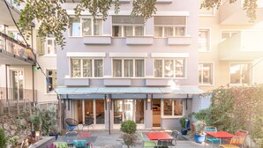 A courtyard with outdoor seating, potted plants, and a building with multiple windows and balconies. - Hotel Birsighof (Basel)