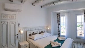 A bedroom with a bed, bedside table, and a window with curtains. - Bozcaada FRESH HOTEL (Bozcaada)