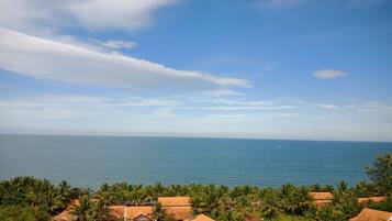A coastal resort with multiple bungalow-style buildings, a swimming pool, and a view of the sea.