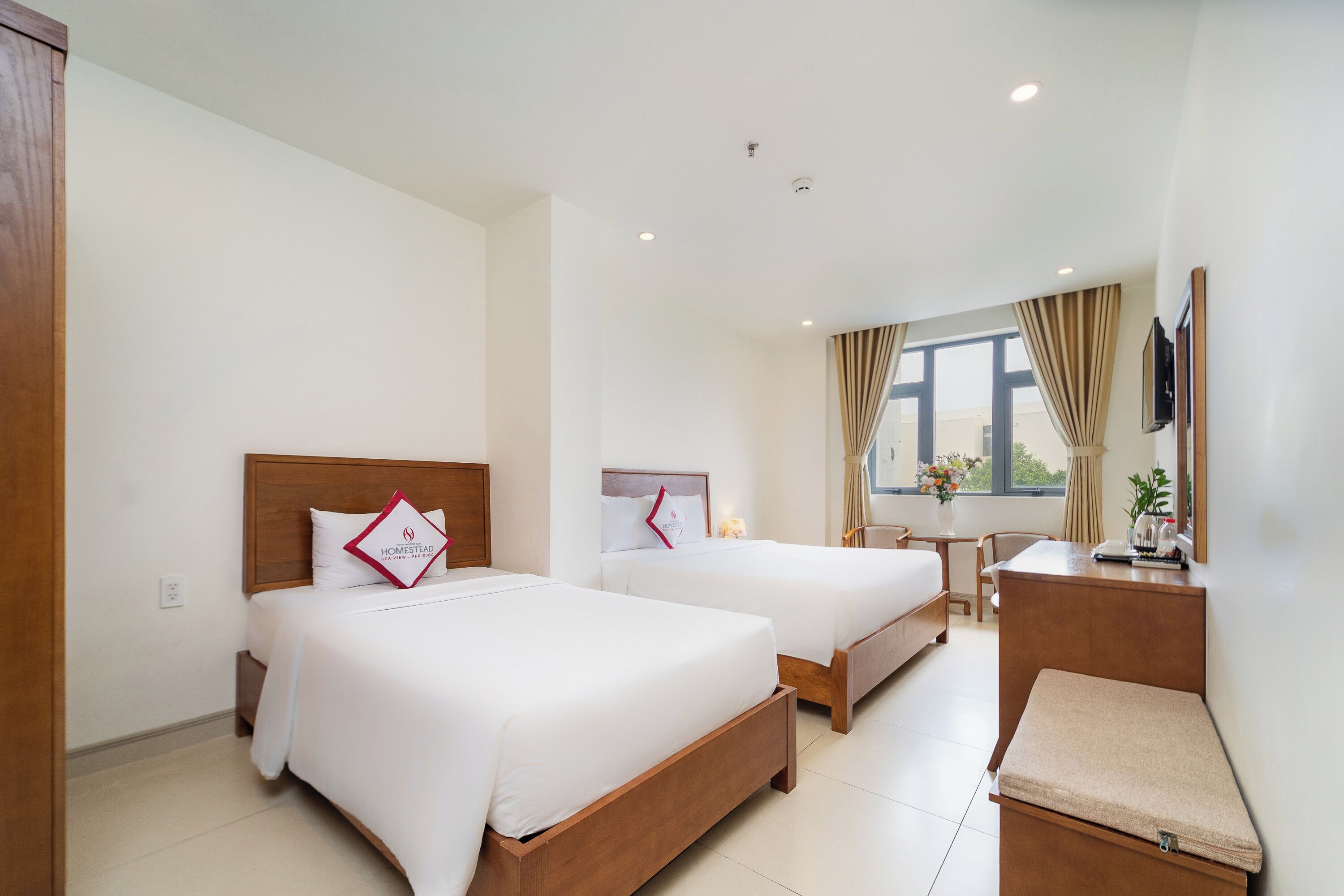 A hotel room with two beds, a desk, and a chair.