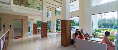 A spacious lobby with a high ceiling, large windows, and a seating area.