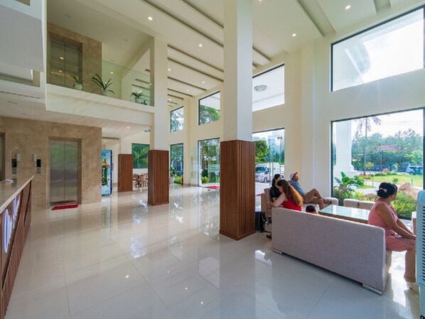 A spacious lobby with a high ceiling, large windows, and a seating area.