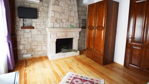 Una habitación con chimenea de piedra, armario de madera y televisor de pantalla plana montado en la pared.