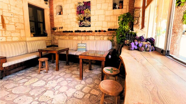 Un espacio exterior acogedor con suelo de piedra, muebles de madera y una pared de ladrillo decorada con arreglos florales.