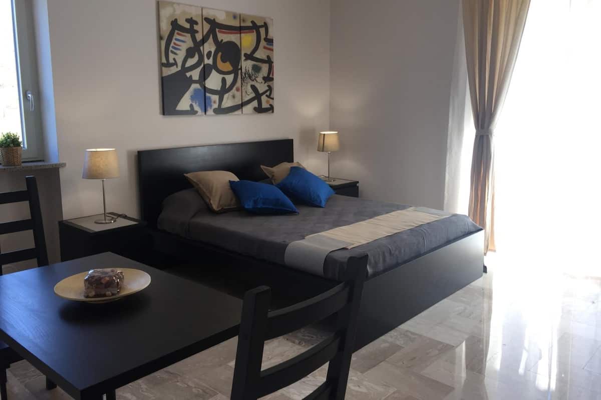 Une chambre à coucher moderne avec un lit, des tables de chevet, un bureau et une chaise.