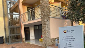 A building with a reception sign, a glass door entrance, and a stone pillar.