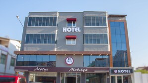 Een hotelgebouw met een bord waarop 'HOTEL' en 'Mobiliya' staat, op de begane grond.