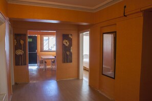 Un pasillo con piso de madera, paredes naranja y una puerta con ventanal.
