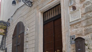 A stone building with a large wooden door and a small window. There is a sign above the door and a light fixture above the window. - B&B Cuore di Vieste (Vieste)
