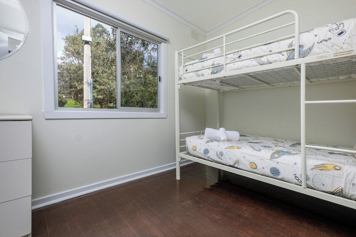 Ein Stockbett mit Fenster, einem Schminktisch und einer Tür.