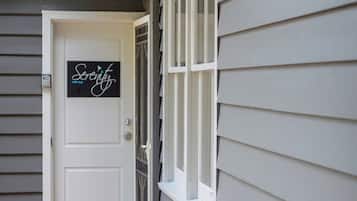 A house with a white door, a window with white shutters, and a wooden deck.