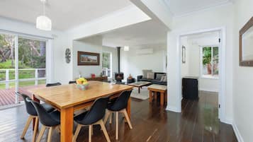 A spacious living area with a wooden dining table, black chairs, and a fireplace.
