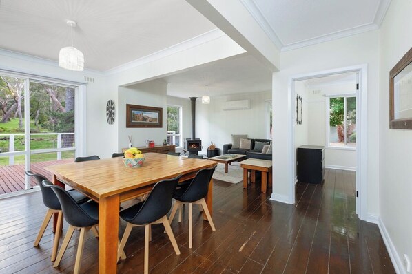 A spacious living area with a wooden dining table, black chairs, and a fireplace.