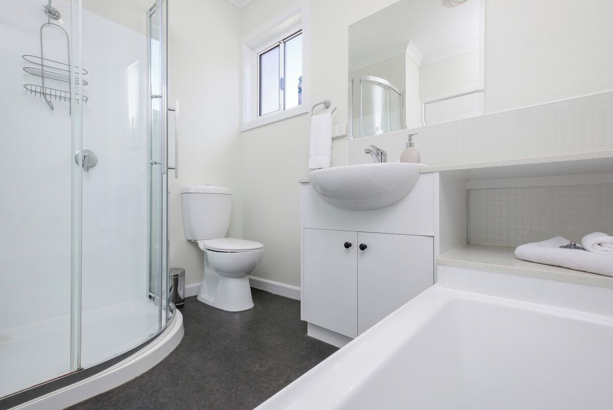 A modern bathroom with a glass shower enclosure, a toilet, a sink, and a bathtub.