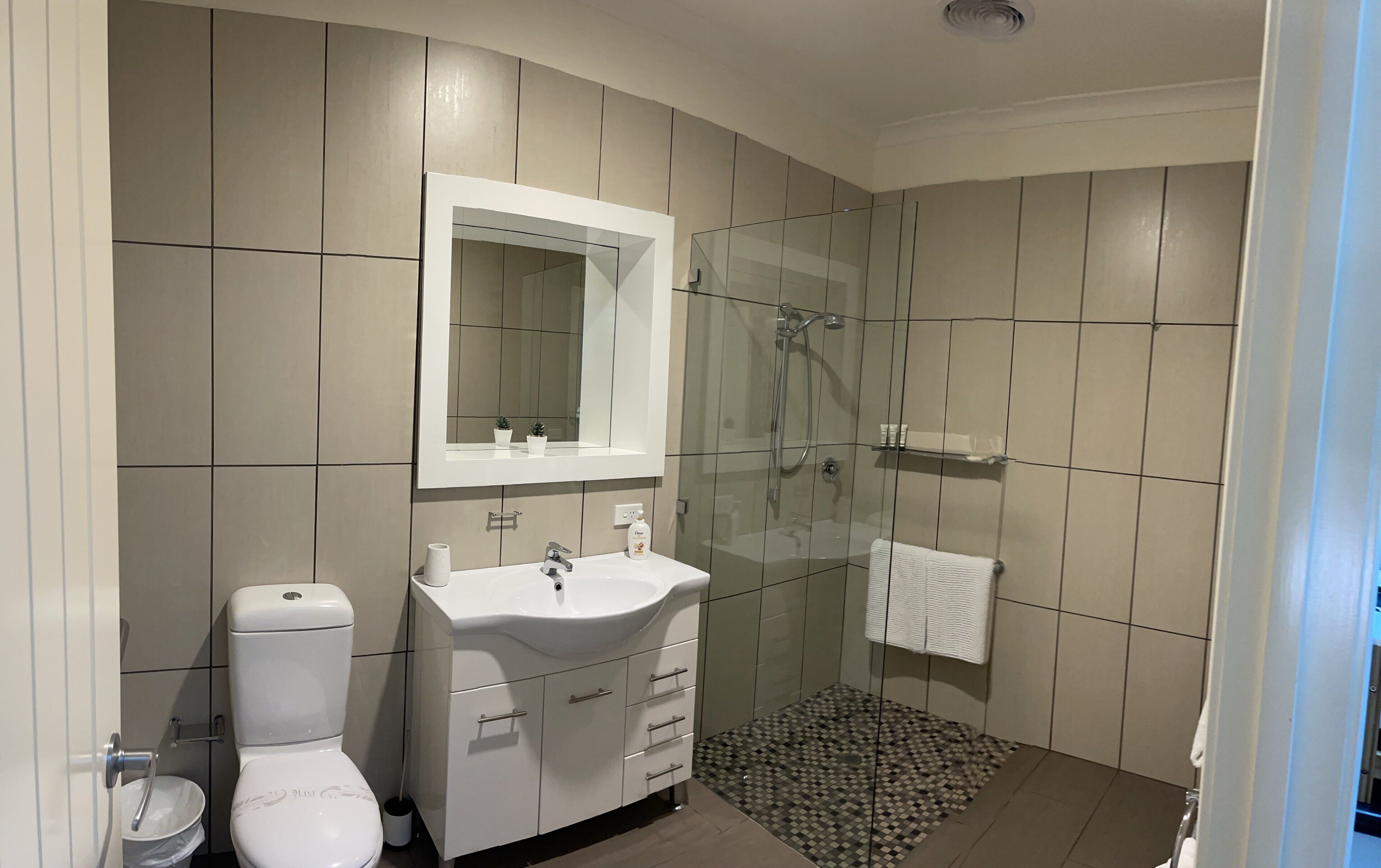 Een moderne badkamer met toilet, wastafel en douche.