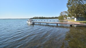 Un lago tranquilo con un muelle que se adentra en el agua, rodeado de árboles y un cielo despejado.