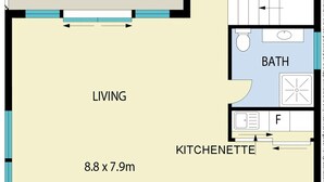 Un plan d’étage comprenant un balcon, un espace de vie, un coin repas, une kitchenette et une salle de bain.