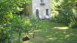 A house with a front porch, a swing, and a garden. - Charming, river front compound  (Bantam)