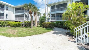 Un hôtel situé en bord de mer, doté de nombreux balcons, de palmiers et d’un sentier de gravier.