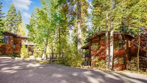 A cabin with a covered porch, surrounded by tall trees and a paved driveway. - Spacious Townhome in the Trees Rocky Ridge Unit #75 (Tahoe City)