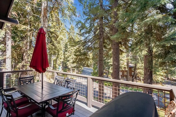 A deck with a table and chairs, surrounded by tall trees. - Spacious Townhome in the Trees Rocky Ridge Unit #75 (Tahoe City)