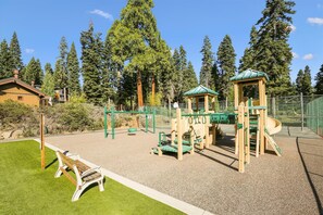 Un parque infantil con un tobogán, estructuras para escalar y una banca.