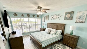 A bedroom with a bed, wooden dresser, nightstands, a ceiling fan, artwork, and a view through the window. - Perfect for a Beach Getaway, Great View and Near the Pool, B2613A (Cape Haze)