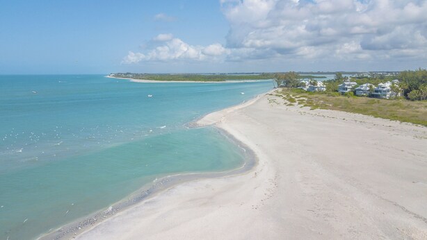 A beach with clear turquoise waters, a sandy shore, and a line of houses in the background. - Perfect for a Beach Getaway, Great View and Near the Pool, B2613A (Cape Haze)