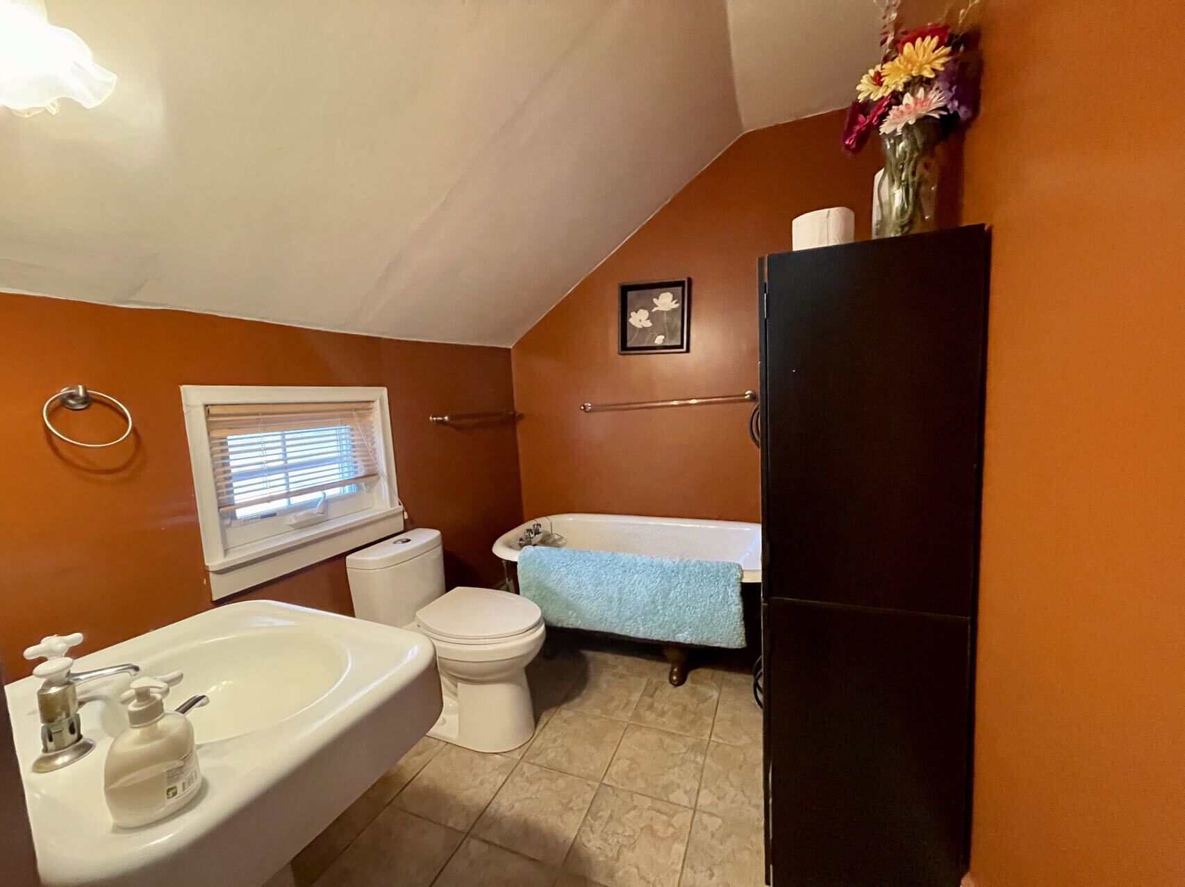 A bathroom with a sink, toilet, bathtub, and a black refrigerator.