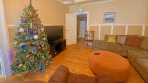 Una sala de estar con un árbol de Navidad, un televisor, un sofá y un reposapiés.
