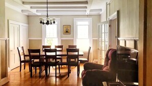 Un comedor amplio con una mesa y sillas de madera, una lámpara de araña y un gran ventanal que proporciona luz natural.