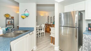 Una cucina moderna con frigorifero in acciaio inossidabile, mobili bianchi e un piano di lavoro blu.