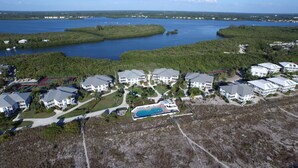 Un quartiere residenziale con diverse case a due piani, una piscina e un ampio specchio d'acqua sullo sfondo.