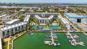 Un puerto deportivo con barcos amarrados, una zona de piscina y un edificio grande de varios pisos.