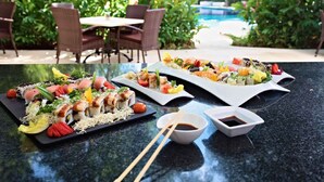Two sushi platters on a table with chopsticks and a small bowl of soy sauce.