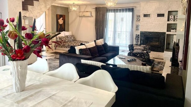 A modern living room with a sofa set, a dining table with a vase of flowers, and a fireplace. - Greek hospitality with Free Double Parking and 1 Gbps WiFi / 9 persons (Κamatero)