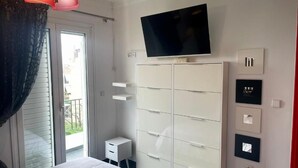 A bedroom with a bed, a TV mounted on the wall, a wardrobe, and a small bedside table. - Greek hospitality with Free Double Parking and 1 Gbps WiFi / 9 persons (Κamatero)