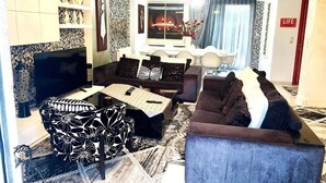 A living room with a sofa set, a television, and a dining area with a table and chairs. - Greek hospitality with Free Double Parking and 1 Gbps WiFi / 9 persons (Κamatero)