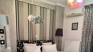 A bedroom with a bed, a bedside table, a lamp, a radiator, and a window with curtains. - Greek hospitality with Free Double Parking and 1 Gbps WiFi / 9 persons (Κamatero)