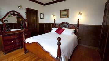A traditional bedroom with a wooden bed, a dresser, and a mirror.