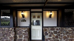 A stone-walled entrance with a white door, two wall-mounted lights, and a sign reading "Ridge Road Tudor Ridge."