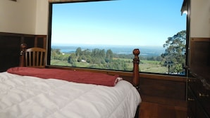 A bedroom with a large window offering a view of a landscape.