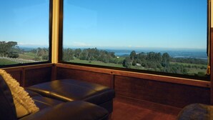 A room with a large window offering a view of a green landscape and distant hills.