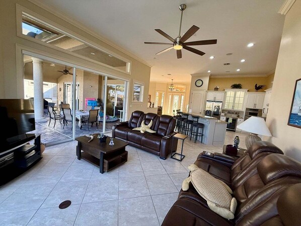 A spacious living room with a large brown leather sofa, a coffee table, and a ceiling fan. - Waterfront 4BR home in Marco Island with heated pool and WiFi (Marco Island)