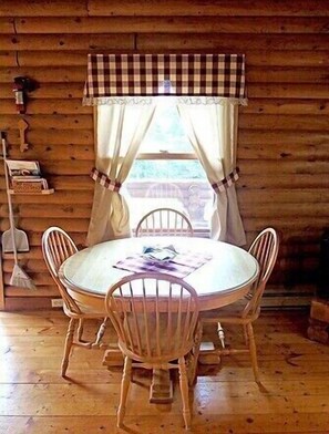 Cozy dining area with a round table and four chairs, featuring a checkered tablecloth and a glass.