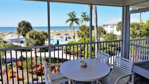 Ein Balkon mit Blick auf den Strand, ein Pool und Palmen.