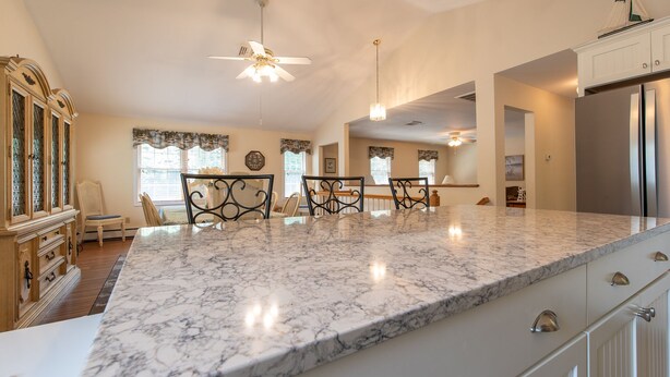 A spacious kitchen with a large marble countertop, wooden cabinetry, and a ceiling fan. - Relax by the sea! 4 bedroom retreat in Bonnet Shores. Central Air sleeps 8A & 2C (Narragansett)