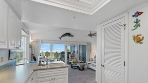 A modern kitchen with white cabinetry, a large window, and a view of the outdoors. - Enjoy a Beautiful Gulf Sunset from the Screened Porch on Resort Villa A3221B (Cape Haze)