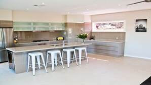 A modern kitchen with a central island, bar stools, stainless steel appliances, and a window with a cityscape view.