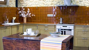 A kitchen with wooden cabinets, a tiled backsplash, a stove, and a breakfast bar. - Ca l'Helena. Enjoy the Penedès, the wine region of Barcelona (Castellet i la Gornal)